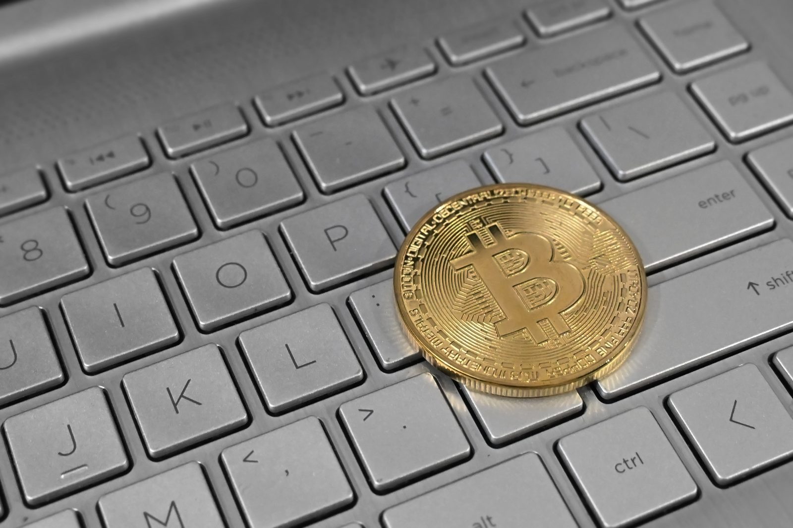 Một đồng Bitcoin vật lý đặt trên bàn phím máy tính xách tay.